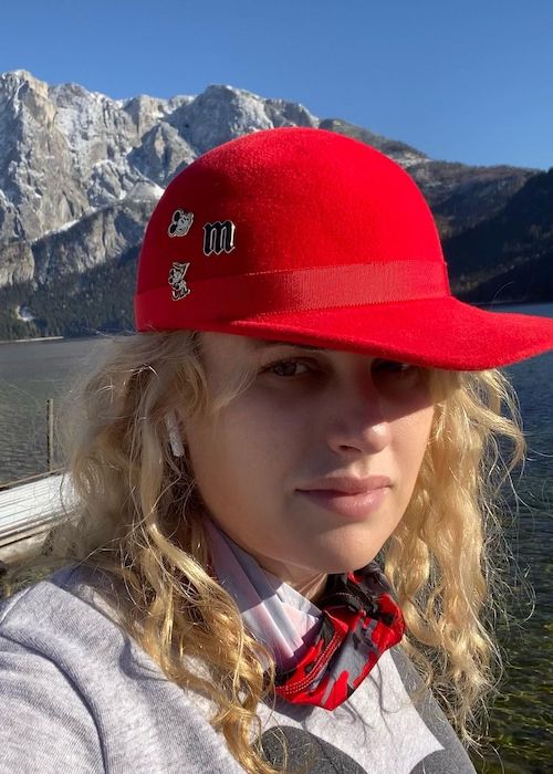 Rebel Wilson wearing red cap and showing pins in 2020