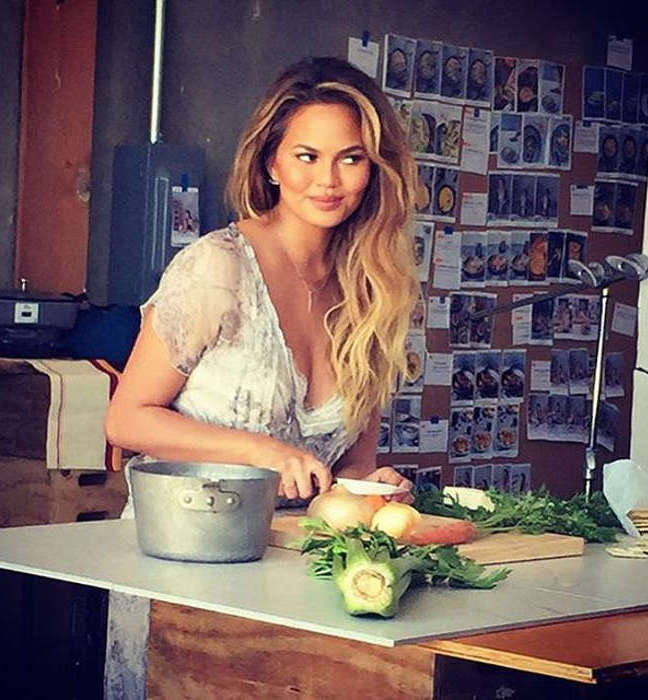 Chrissy Teigen in the kitchen cutting veggies