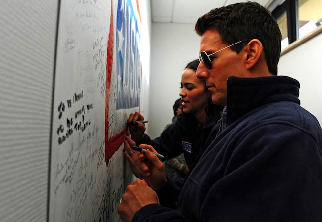 Tom-Cruise-and-Paula Patton signing a USO poster while on a Contingency Aeromedical Staging Facility tour in Germany in December 2011