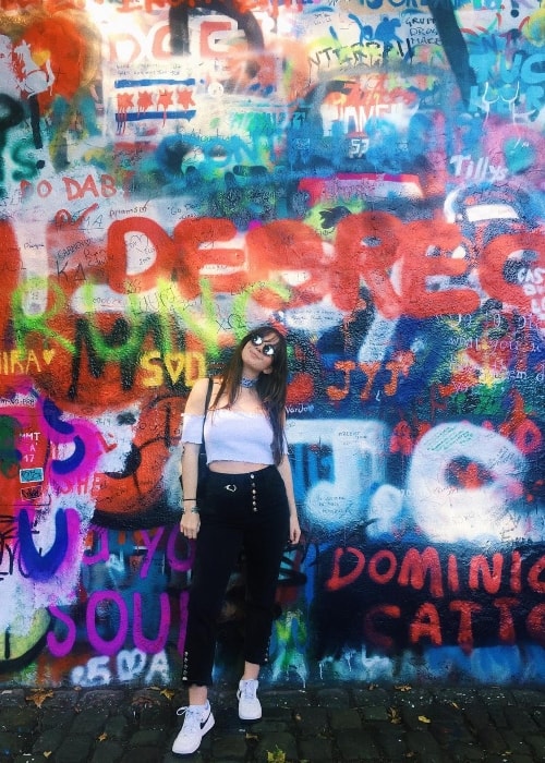 Emma Taylor posing in front of the John Lennon Wall in October 2017