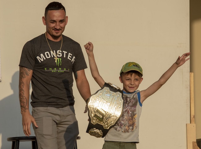 Max Holloway with a child from the audience holding his championship belt at the USO Spring Tour at Yokota Air Base Japan on April 22, 2018