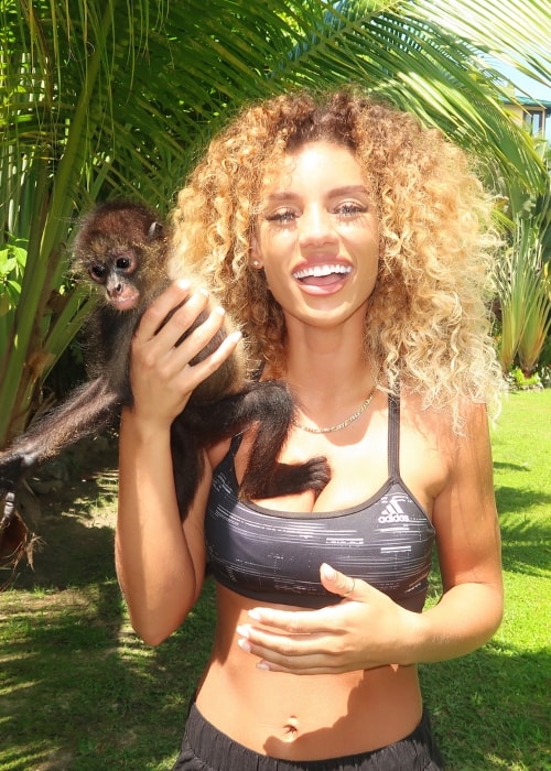 Jena Frumes posing with a Spider Monkey in Roatán, Islas De La Bahia, Honduras in August 2018