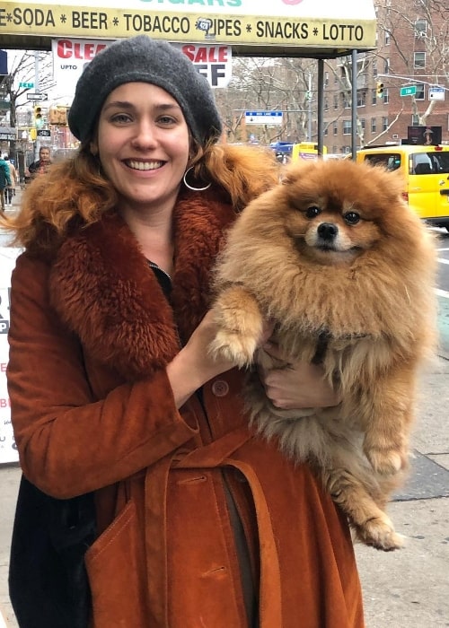 Lola Kirke posing with a furry dog in December 2018