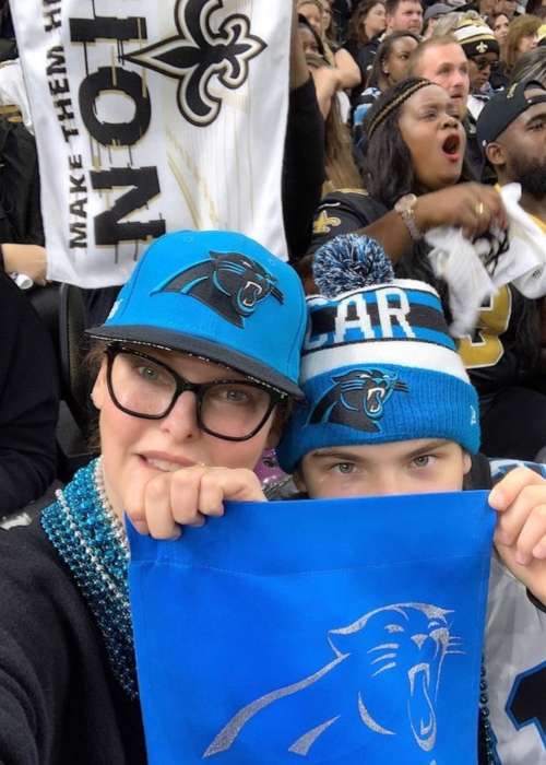 Linda brandishing a Carolina Panthers flag with her son Augustin James during their match against New Orleans Saints in December 2018