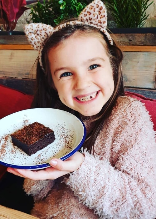 Sienna Fizz as seen while smiling for the camera with a plate of her Salted Caramel Brownie at Purezza in March 2019