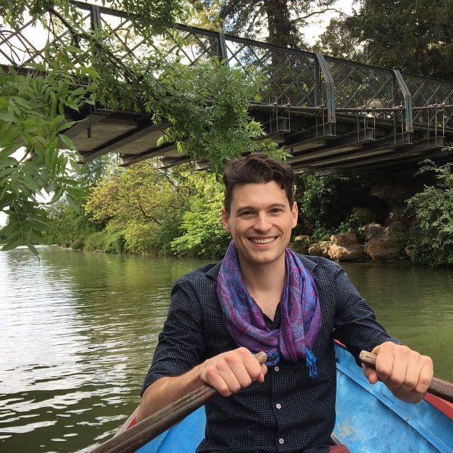 Bryan Dechart smiling for a picture while on a rowboat in Paris, France along with his beloved lady, Amelia Rose Blaire, in May 2017