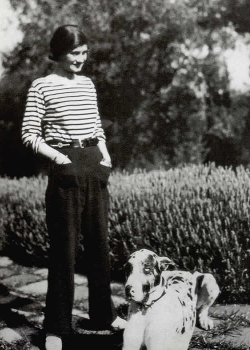 Coco Chanel as seen while standing beside a dog in 1928