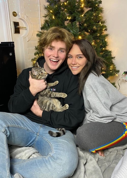 Alex Warren posing for a Christmas picture along with Kouvr Annon and their cat named Stormy in December 2019