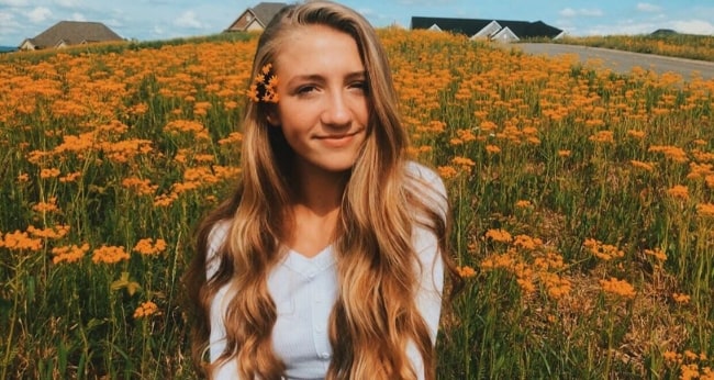 Emma Rayne Lyle posing for a picture with flowers in the background in May 2019