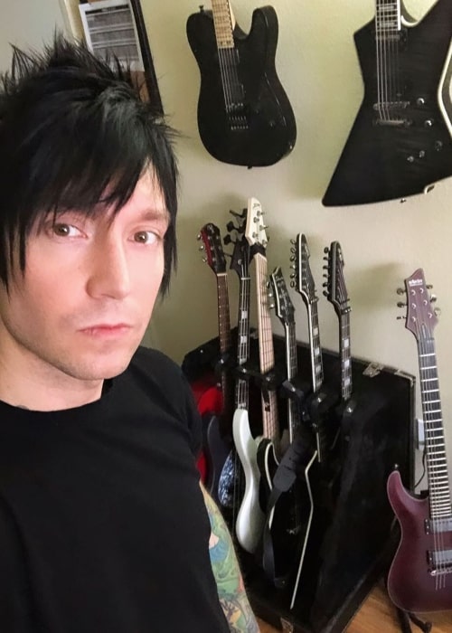 Jake Pitts taking a selfie with his guitar collection in the background in November 2019