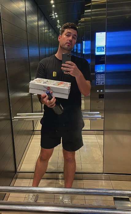 Hayden James as seen while taking a mirror selfie with his pizza and wine in February 2020