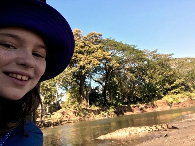 Alexa Swinton as seen while taking a selfie with a crocodile in the background in September 2019