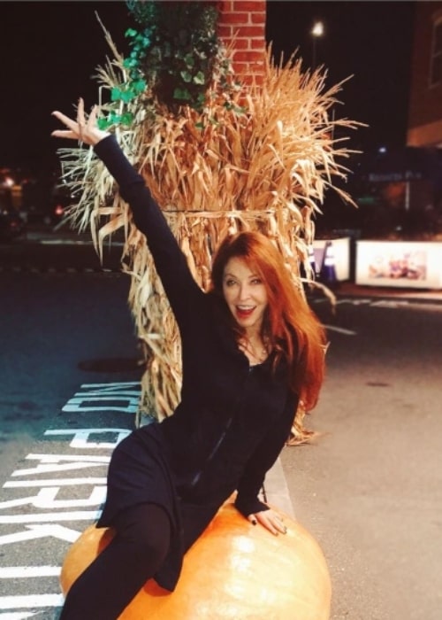 Cassandra Peterson having fun sitting on a pumpkin in November 2019