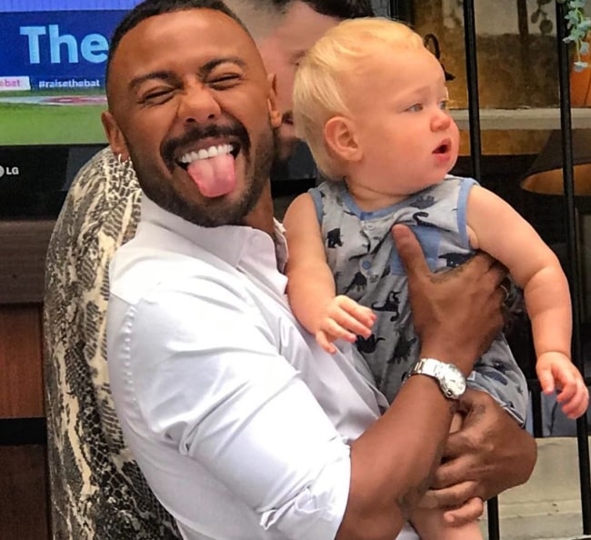 Marcus Collins posing for a goofy picture while holding his nephew Prince Cassius Lowe in Liverpool, England