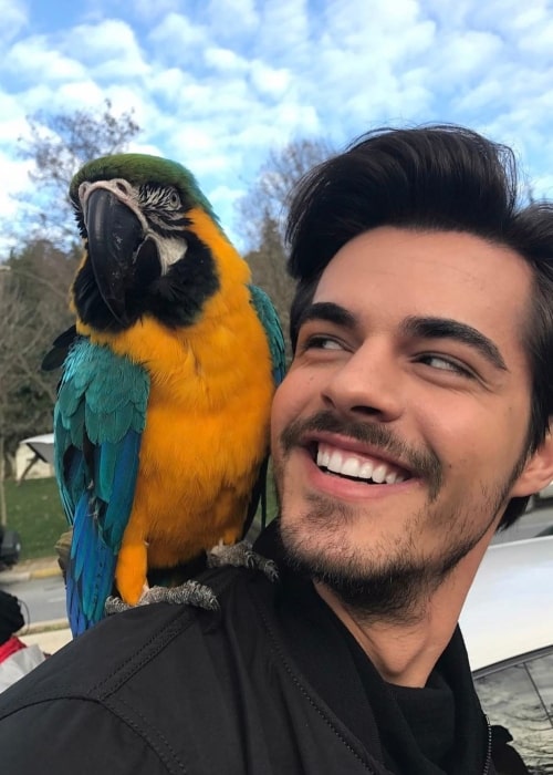 Berk Atan as seen in a selfie that was taken with a beautiful parrot on his back while on set in February 2017