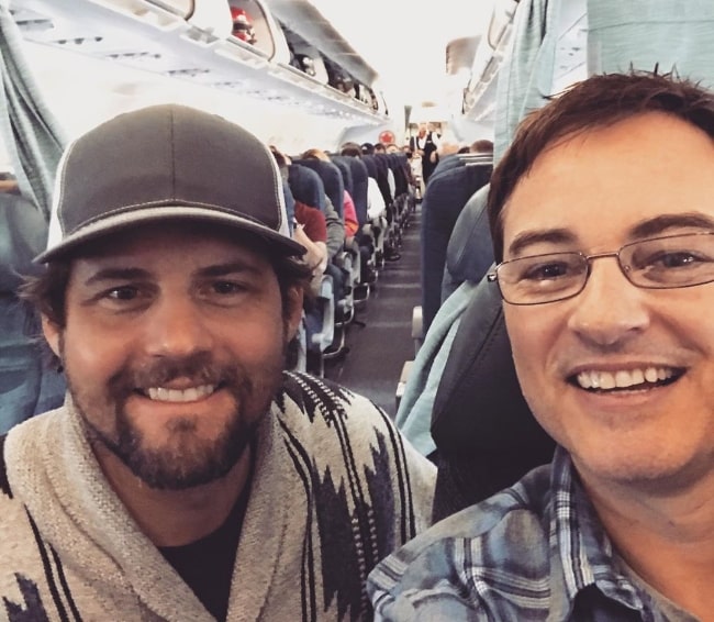 Kerr Smith (Right) smiling in a selfie alongside Kristoffer Polaha at Vancouver International Airport in March 2020