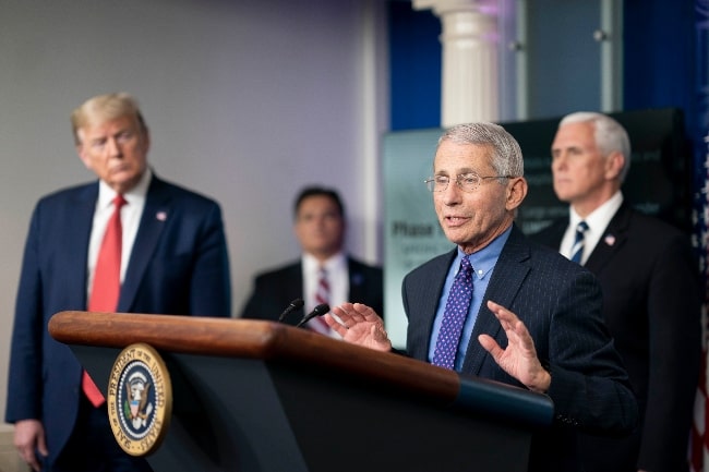 Anthony Fauci pictured while speaking to the White House press corps on COVID-19 in April 2020, watched by President Donald Trump (Left) and Vice President Mike Pence (Right)