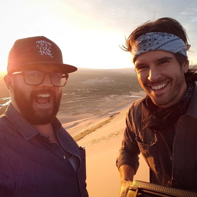 Graham Wardle (Right) smiling in a selfie alongside Peter Harvey at the top of the dunes in Mongolia