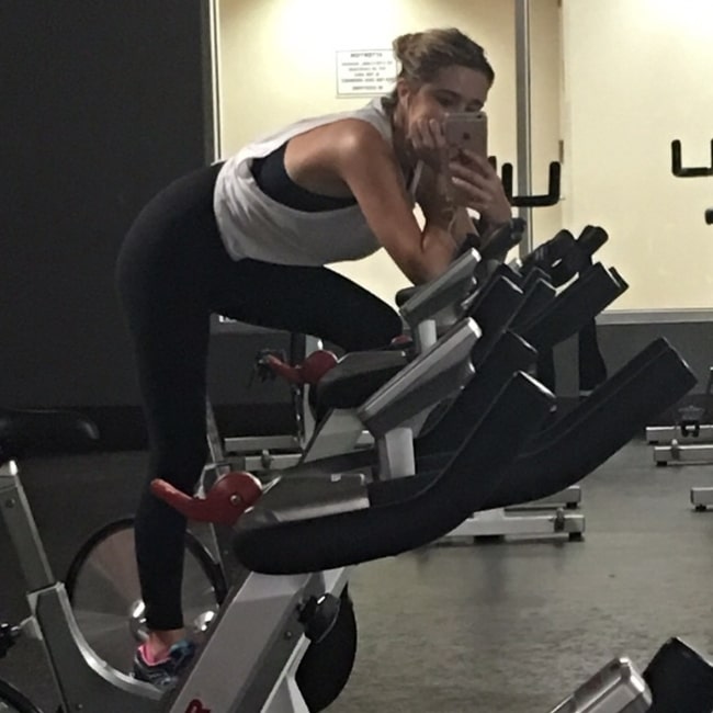 Amy Shiels clicking a mirror selfie while working out in March 2019