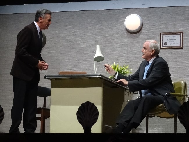 John Cleese and Michael Palin (Standing) during the 'Argument Clinic' sketch at 'Monty Python Live (Mostly)' in 2014