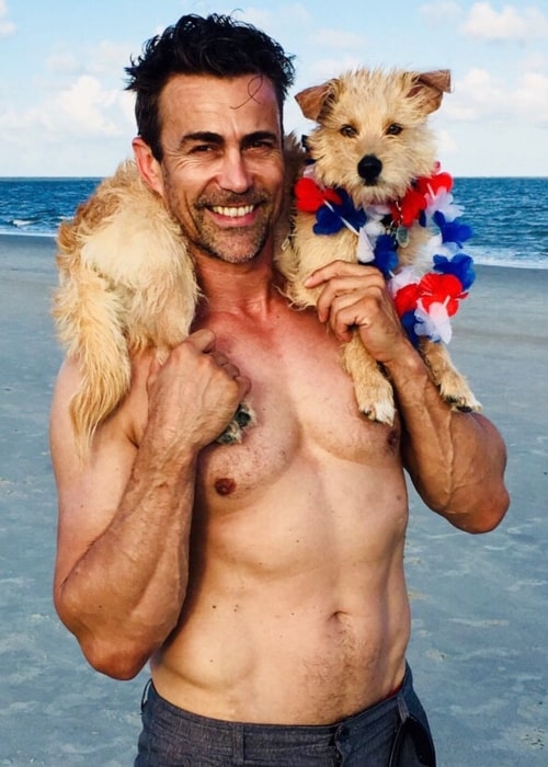 Daniel Bernhardt as seen while posing shirtless for the camera with his dog