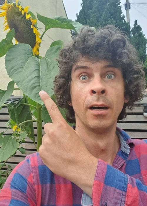 Andy Day as seen while taking a selfie with a sunflower in the background in July 2020