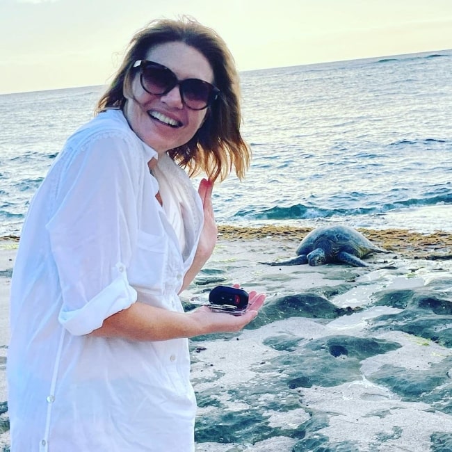 Kathleen Rose Perkins smiling for a picture with a sea turtle in the background in May 2021