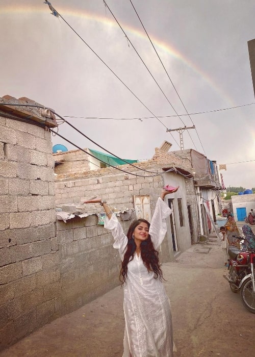 Sajal Aly posing for a picture with a rainbow in the backdrop in August 2021