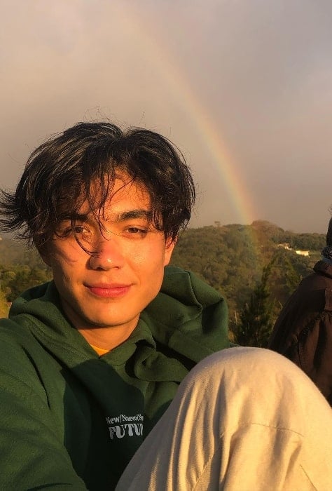 William Gao posing for a picture with a rainbow in the backdrop in Costa Rica in January 2022