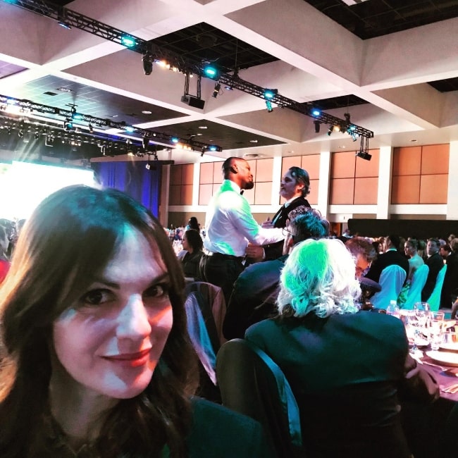 Jessica Pressler in a selfie with actors Jamie Foxx and Joaquin Phoenix in the background at the Palm Springs Convention Center