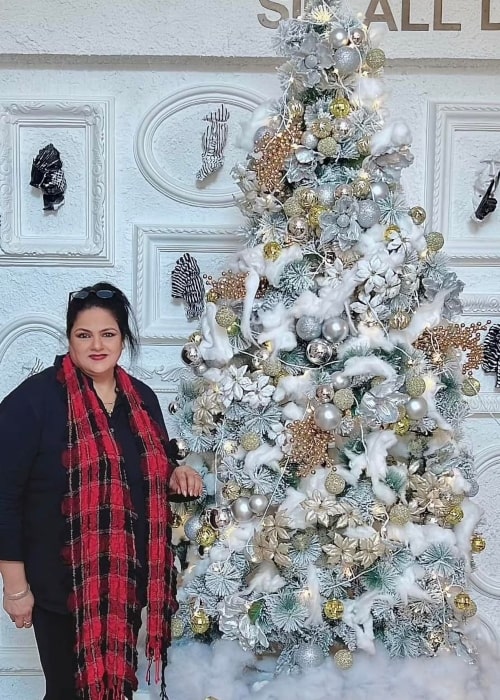 Guddi Maruti posing for a picture with a Christmas tree in December 2022