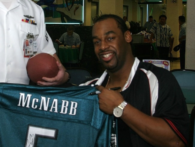 Donovan McNabb smiling for the camera as he signed a football jersey belonging to Storekeeper 2nd Class of Fleet Industrial Supply Center, Pearl Harbor in 2004
