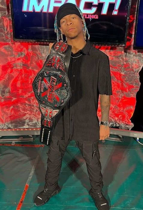 Lio Rush posing for the camera with Impact X Division belt in 2023