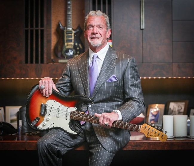 Jim Irsay as seen while smiling for the camera with the Fender Stratocaster played by Bob Dylan at the Newport Folk Festival