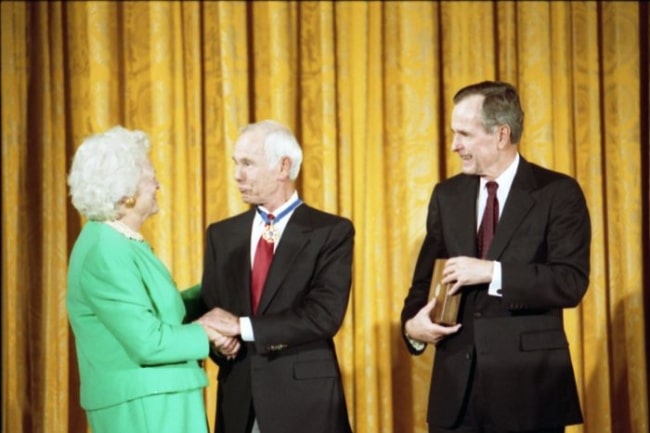 Johnny Carson (Center) as seen while being awarded the Presidential Medal of Freedom by President George H. W. Bush and First Lady Barbara Bush in 1992