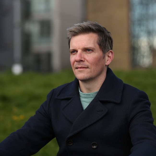Nigel Harman as seen while smiling in a still in October 2023